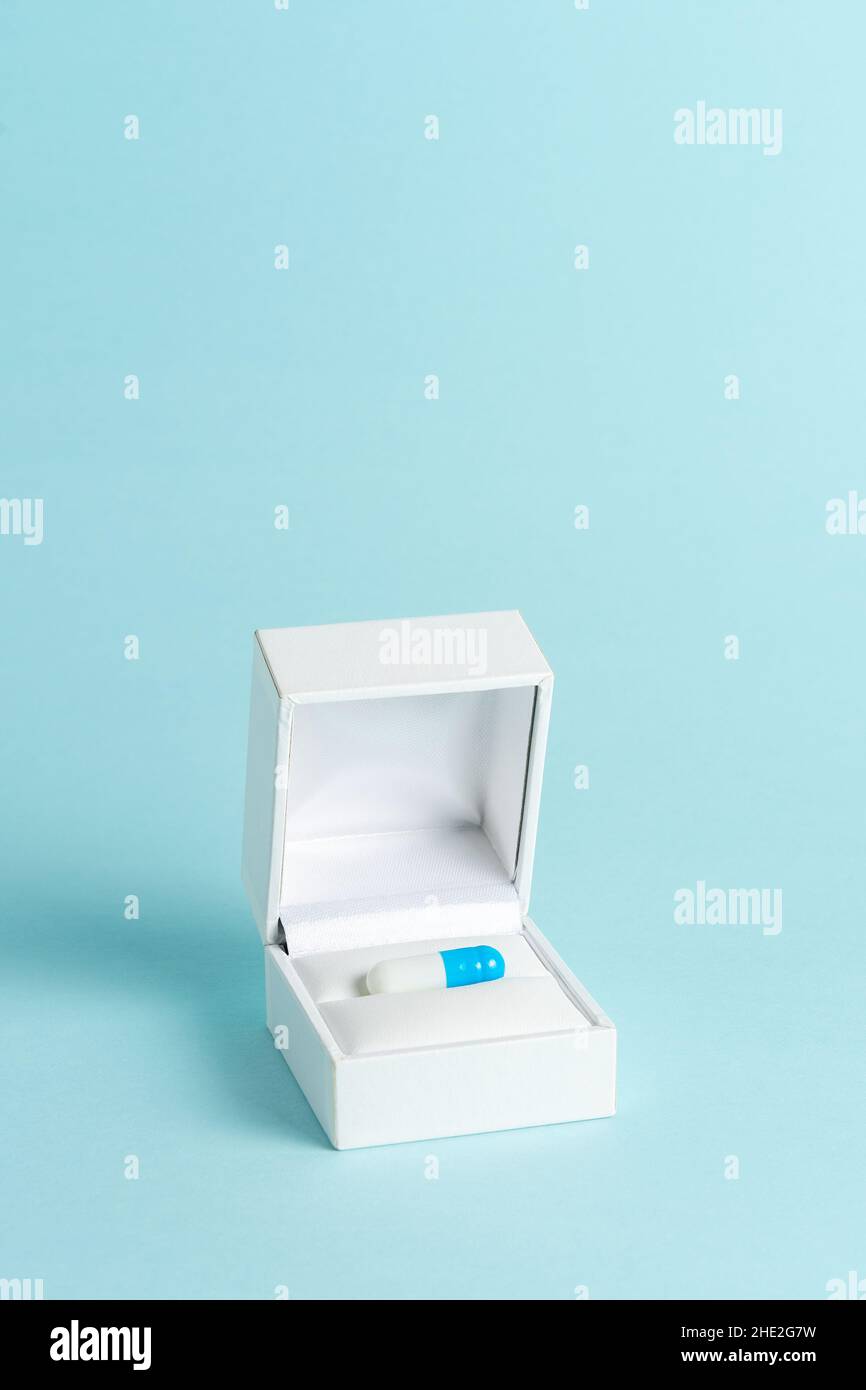 Blue pill in engagement ring box on pastel blue background. Minimal creative concept. Stock Photo
