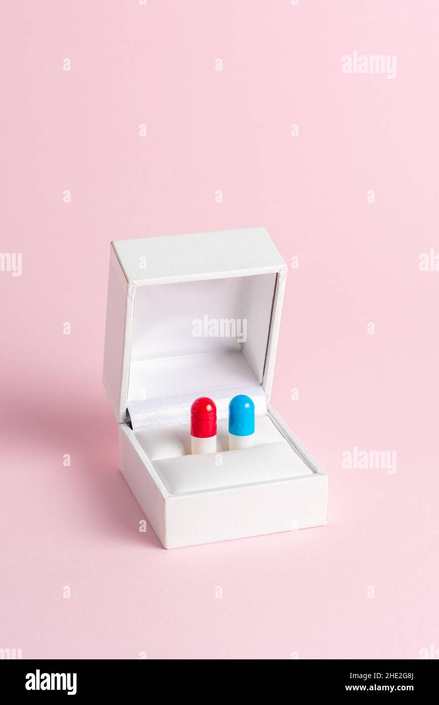 Creative composition with red and blue pill in engagement ring box on blue background. Minimal concept. Stock Photo