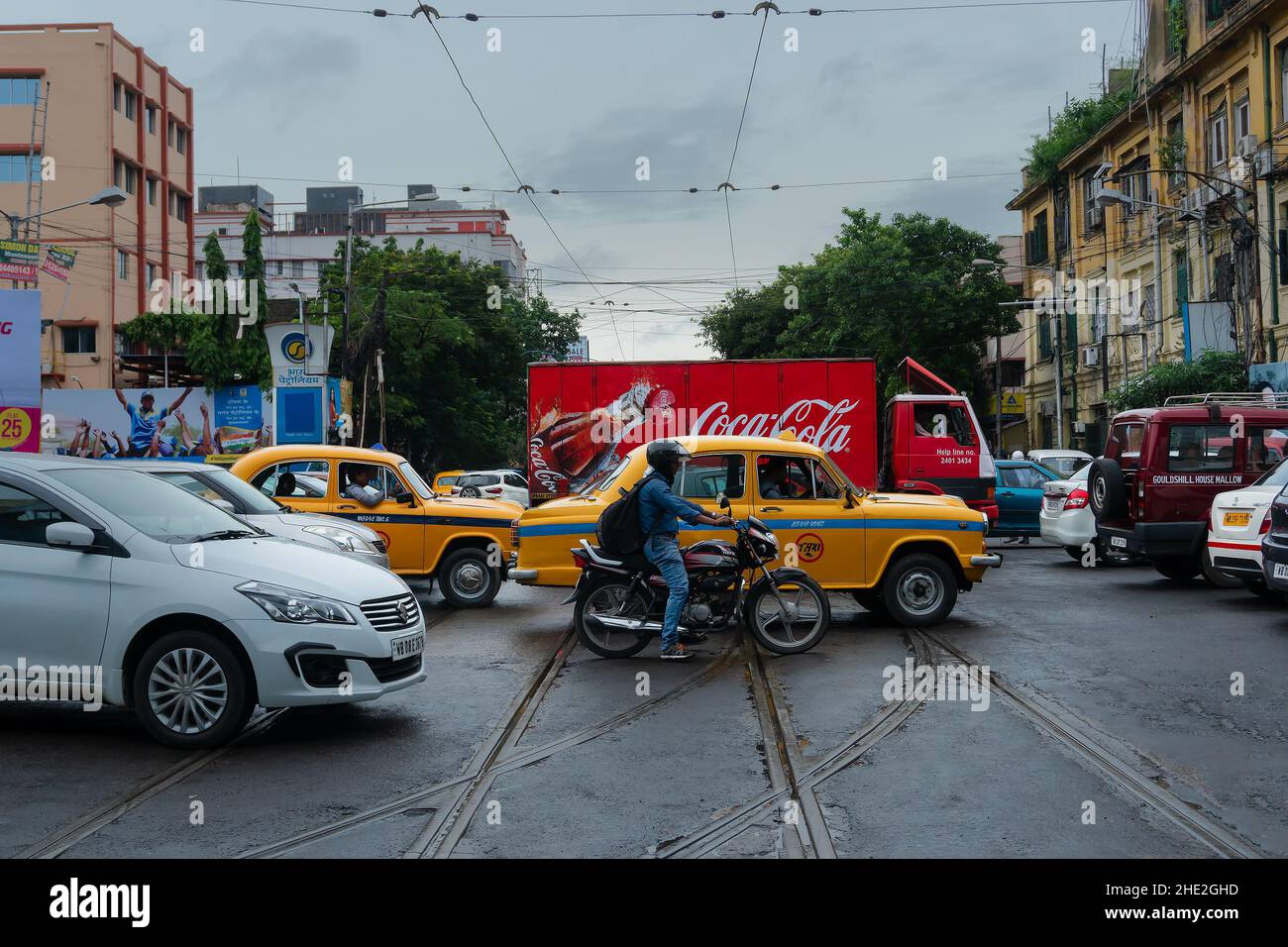 Kolkata, West Bengal, India - 6th August 2019 : Yellow cab, motorbike and van passing, busy city traffic of Kolkata road. Stock Photo