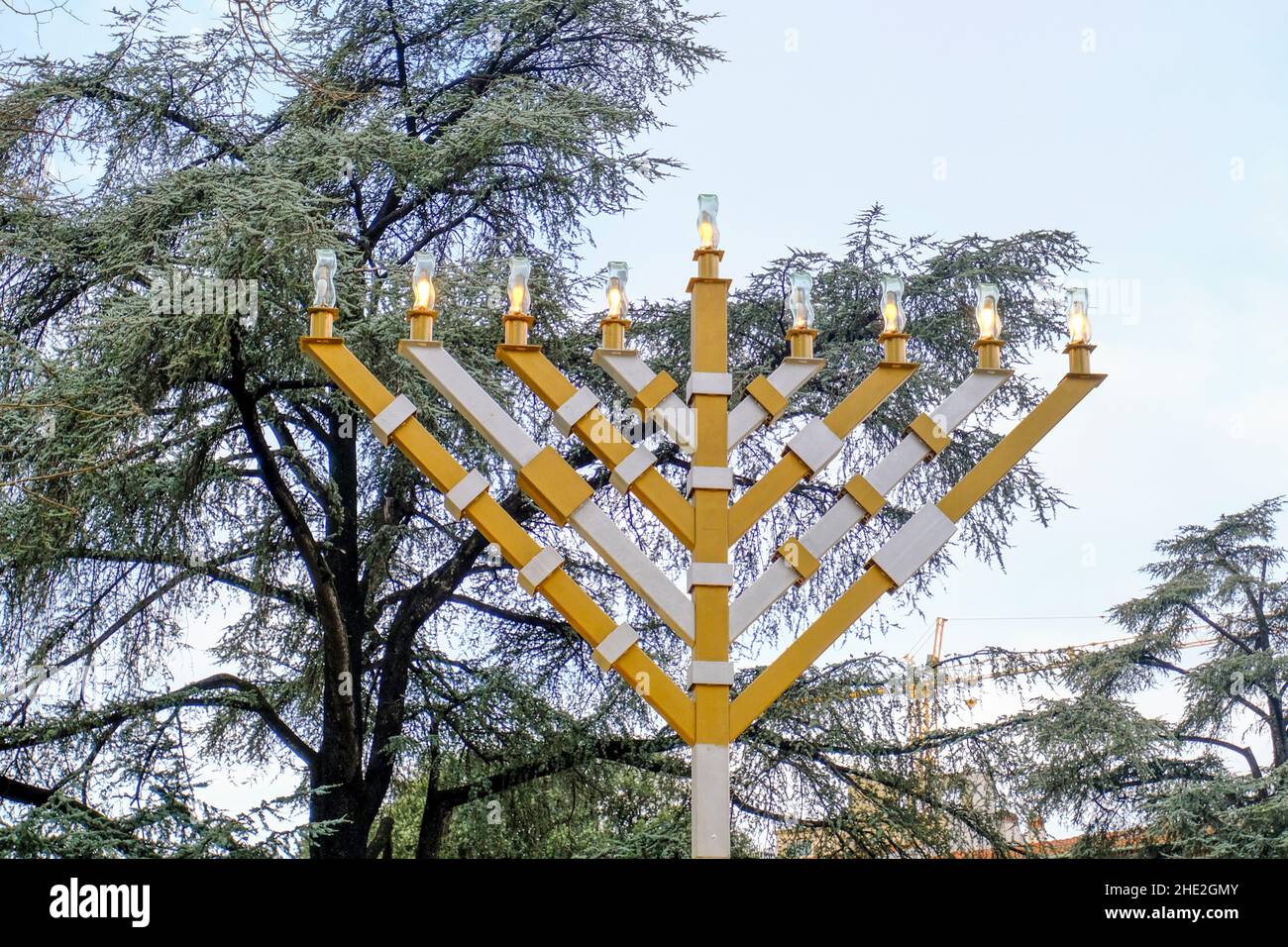 Hanukkah menorah, hanukkiah, nine-branched candelabrum lit during. Jewish holiday of Hanukkah. Hanukkah symbol on the street of the city across the sk Stock Photo