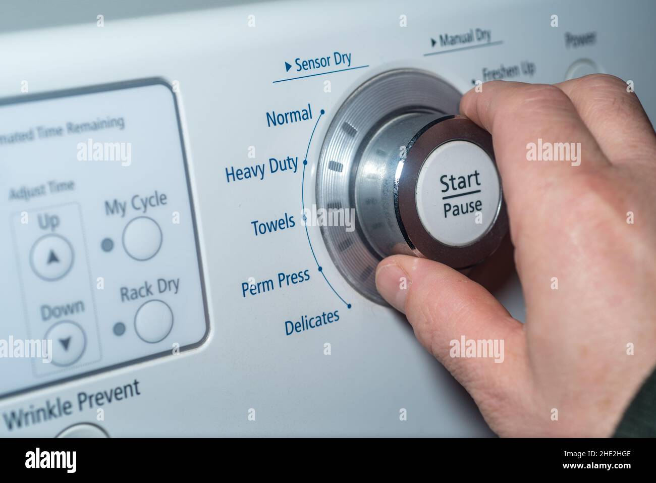 Hand turning the knob of the dryer to adjust the setting Stock Photo