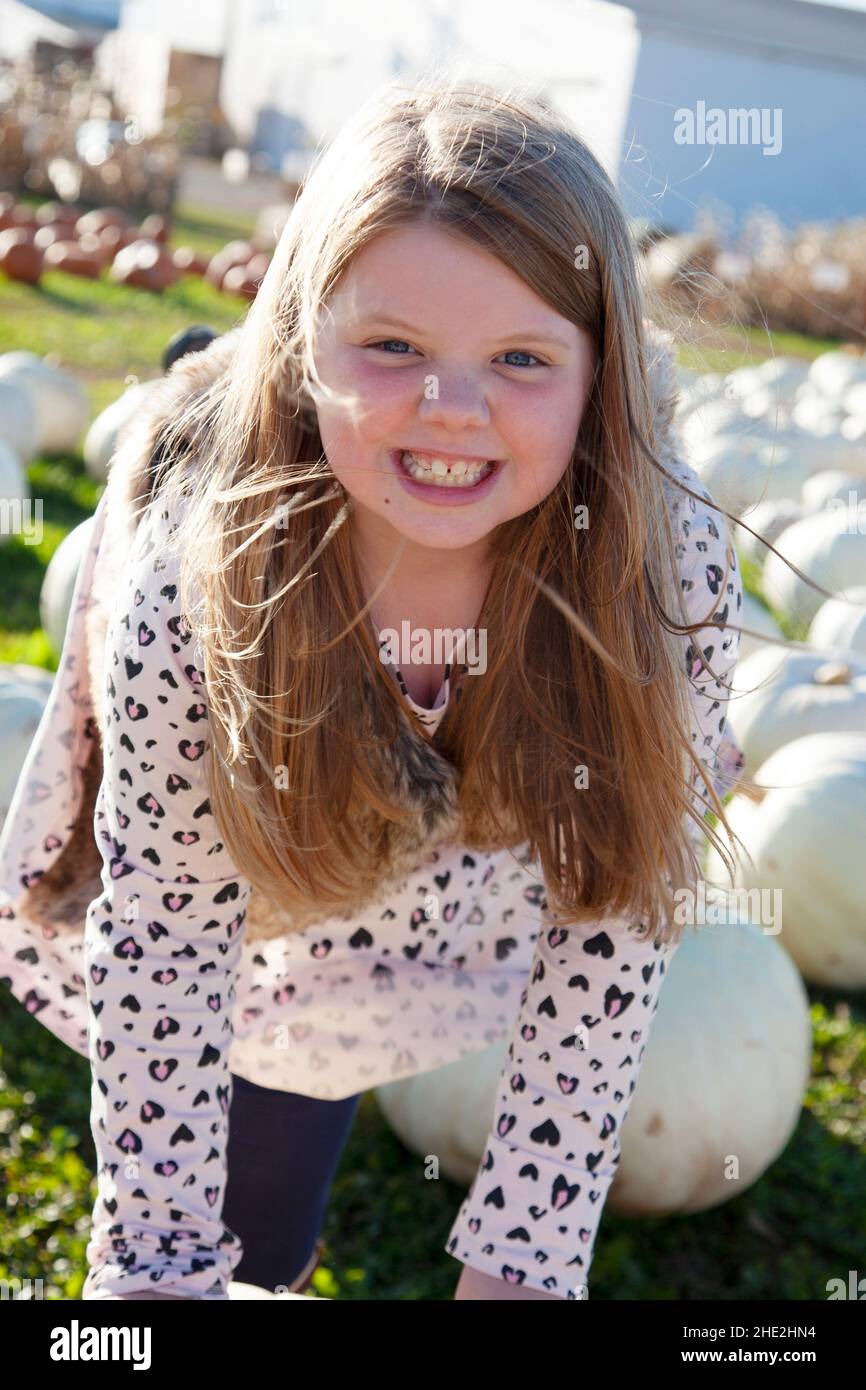 smiling girl on a field of pumpkins playing and grinning Stock Photo