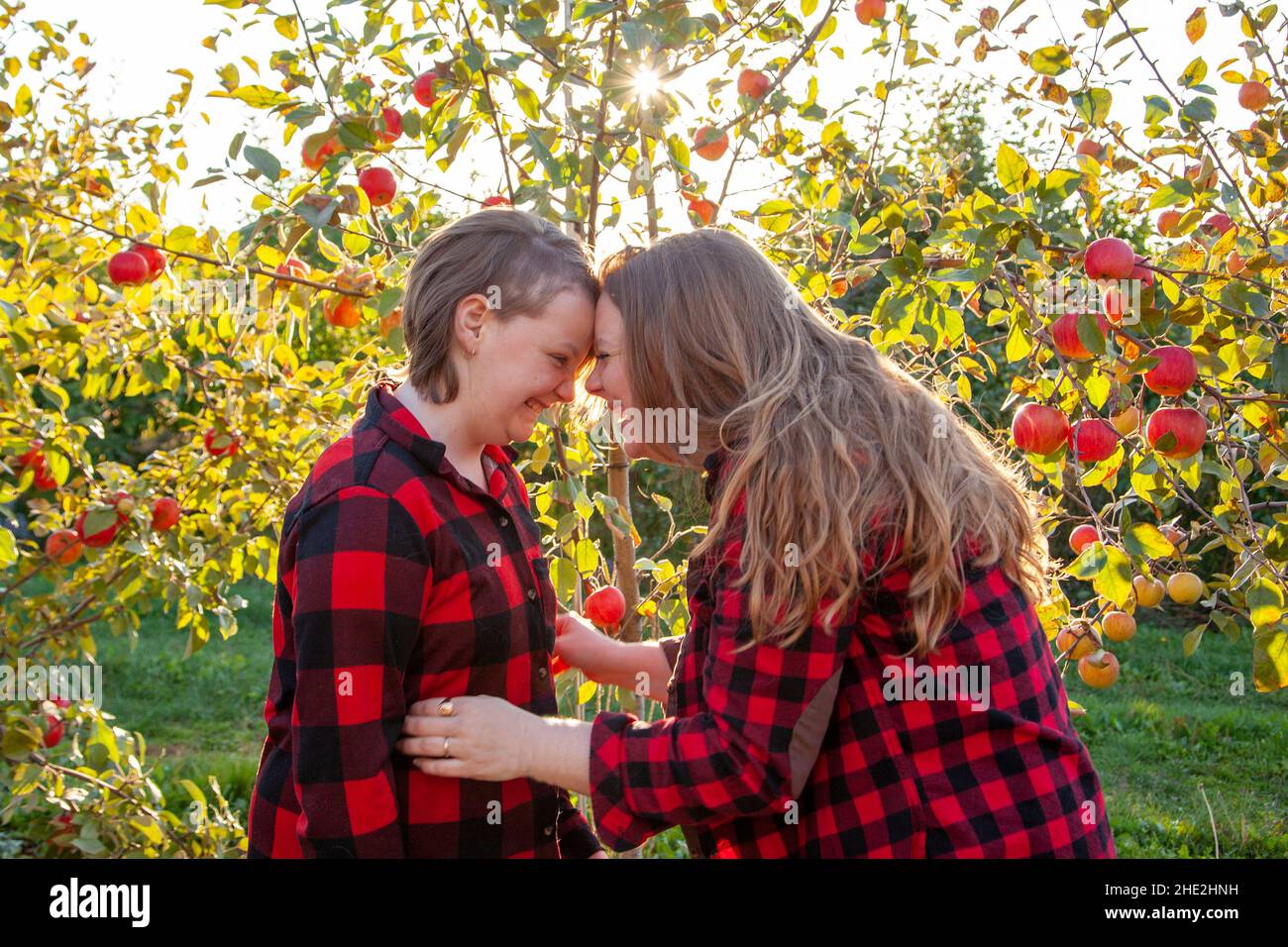 mom and child both wearing plaid smile together in the sun and hold each other Stock Photo
