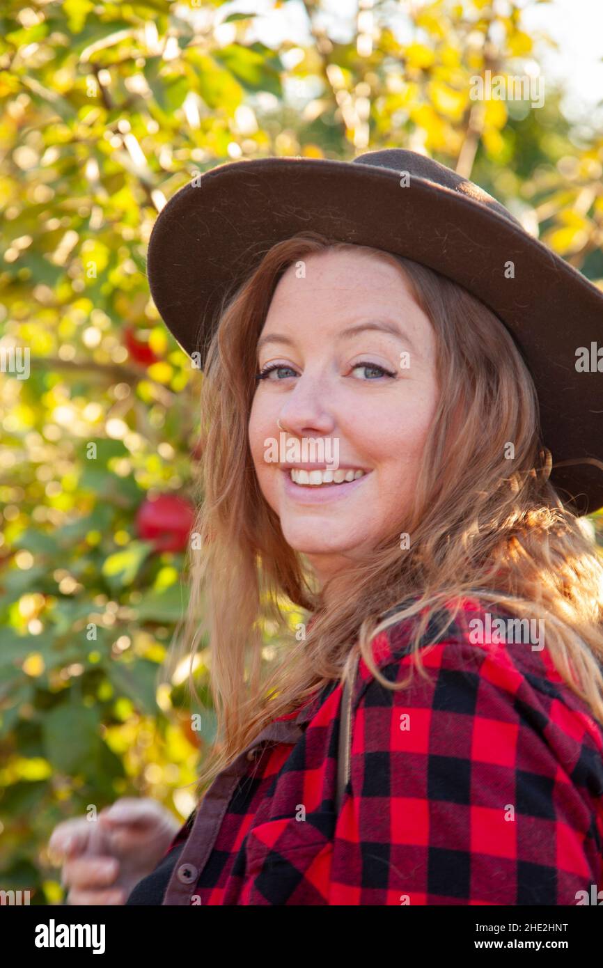 portrait of a gorgeous woman in a hat in plaid in an orchard Stock Photo