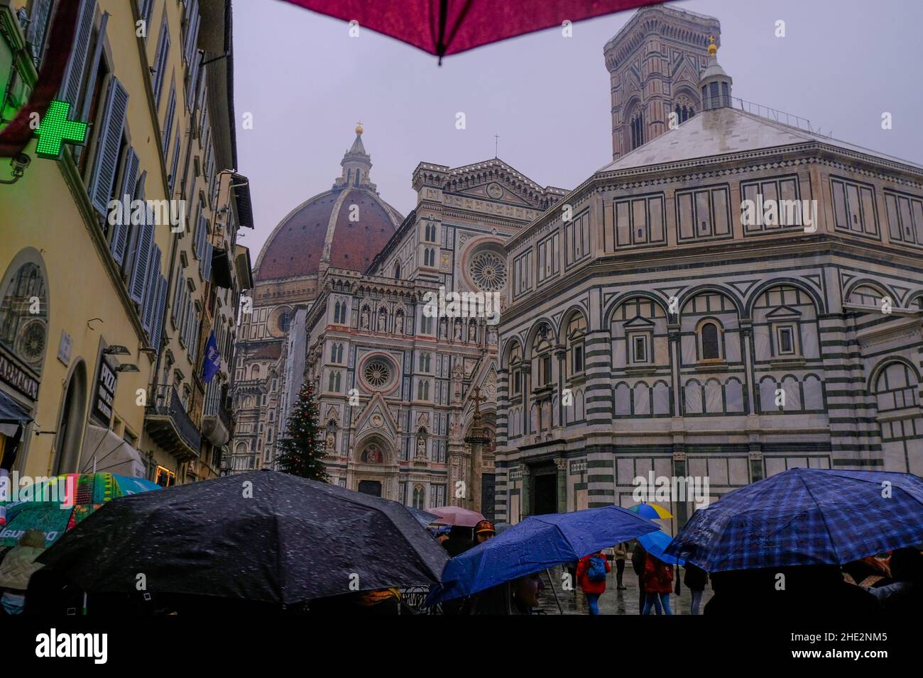 Florence, Italy: Dome of Santa Maria del Fiore close-up across dramatic sky, buildings, across people with umbrellas on a rainy day. Stock Photo