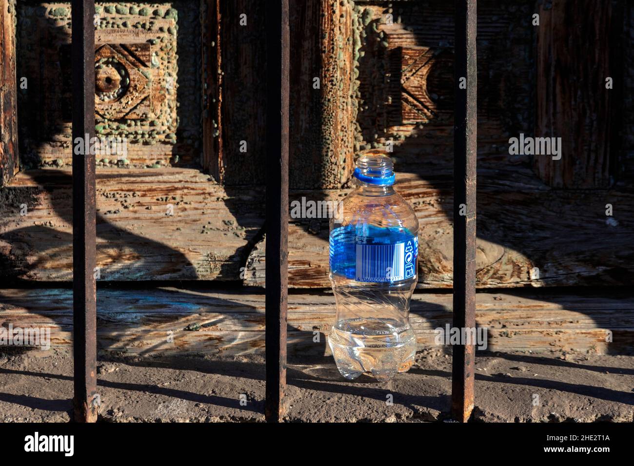 LITTER A DISCARDED PLASTIC WATER BOTTLE PLACED BESIDE AN OLD WOODEN WINDOW SHUTTER Stock Photo