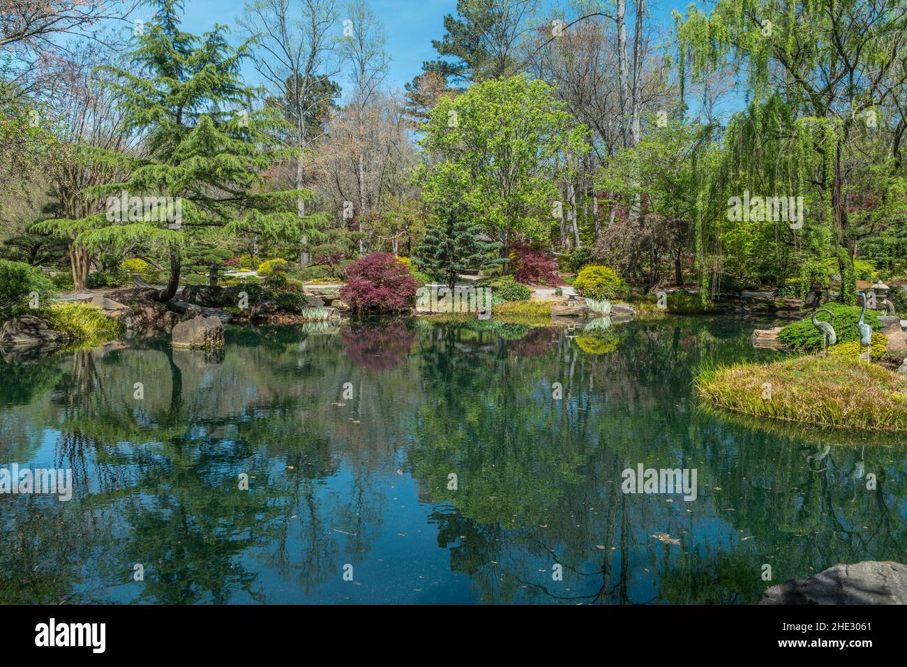 A beautiful tranquil setting at the Japanese garden with vibrant colors of spring emerging reflective in the pond at Gibbs gardens in the north Georgi Stock Photo