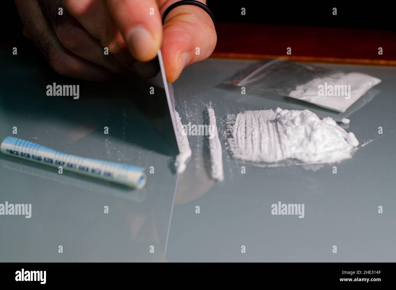 The man divides the cocaine into strips and then snorts. Narcotic concept. Stock Photo