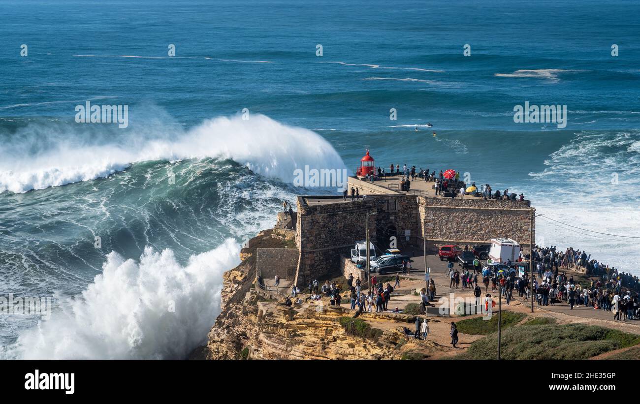 Giant waves breaking near the Fort of Sao Miguel Arcanjo Lighthouse in Nazare, Portugal. Nazare is famously known for having the biggest waves in the Stock Photo