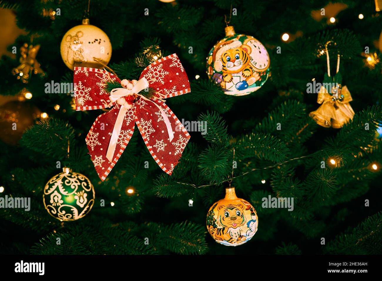 Christmas tree decorated with Christmas light and balls with a picture of a tiger and a red bow Stock Photo