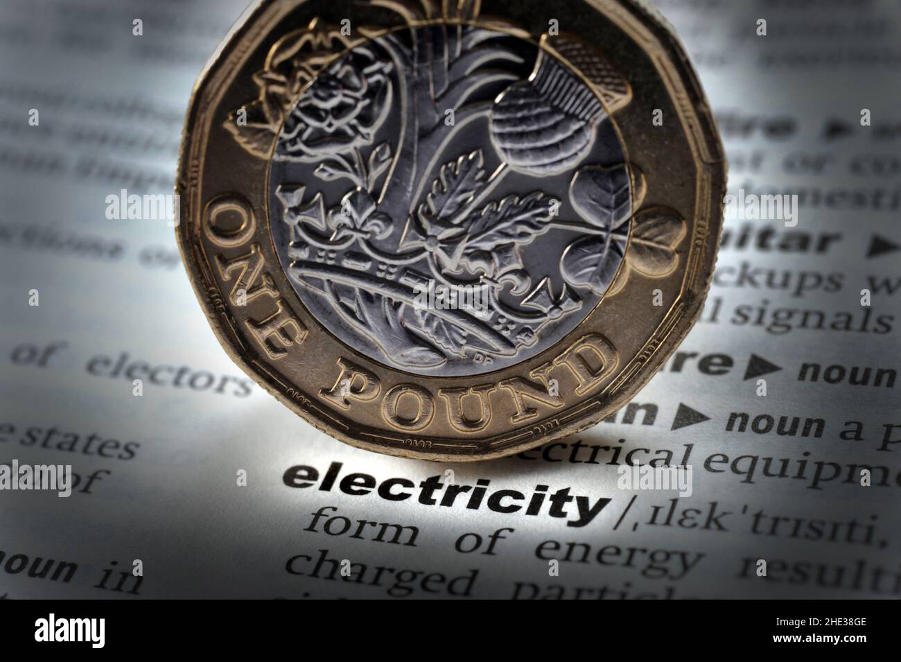 DICTIONARY DEFINITION OF WORD ELECTRICITY WITH ONE POUND COIN RE FUEL ENERGY COSTS HEATING RISING HOUSEHOLD BUDGETS ETC UK Stock Photo