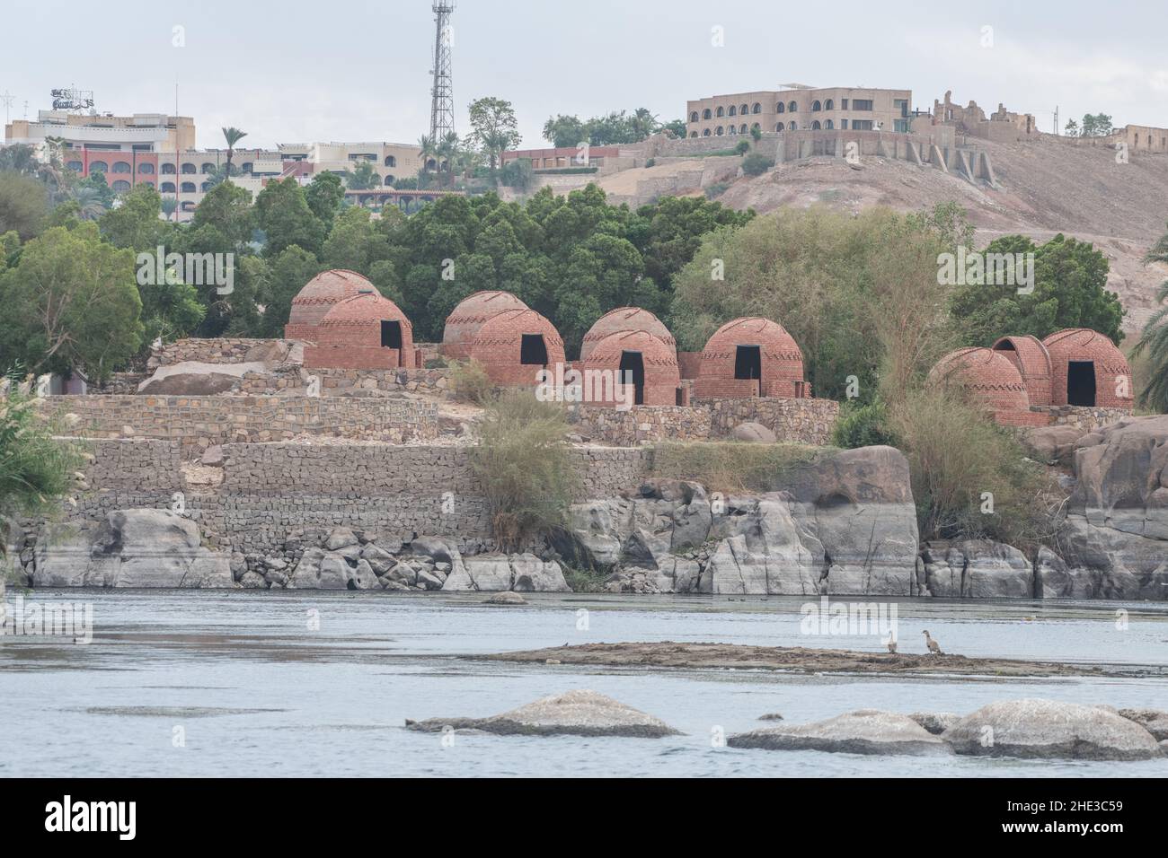 Red brick houses that were illegally constructed along the Nile river in Aswan city, Egypt and now sit empty awaiting demolition. Stock Photo