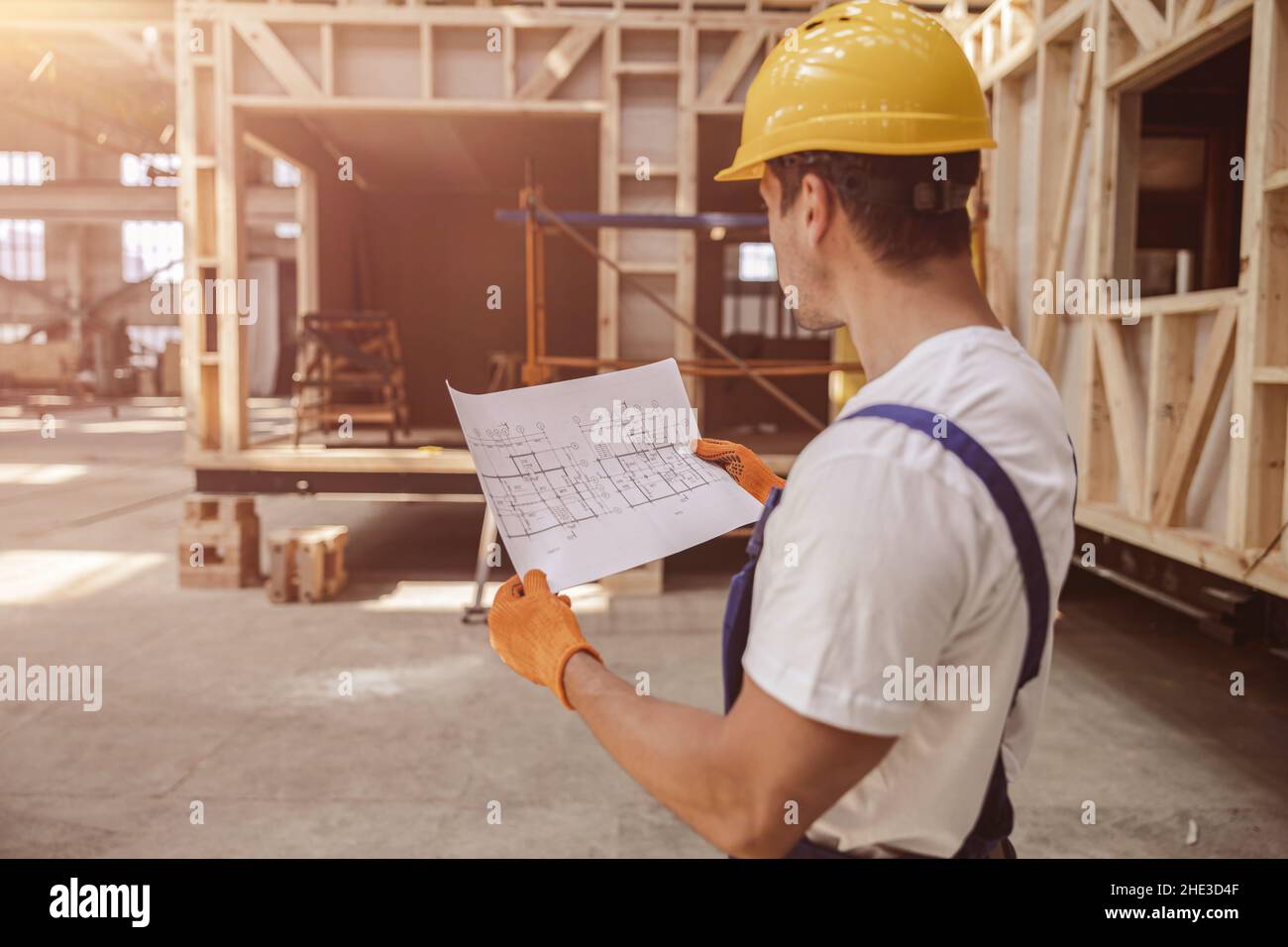 Male builder working with architectural plan at construction site Stock Photo