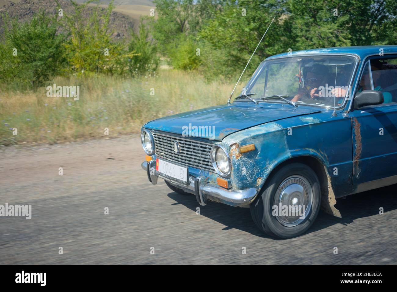 Old blue soviet Lada VAZ-2101 drives on road in Kyrgyzstan Stock Photo