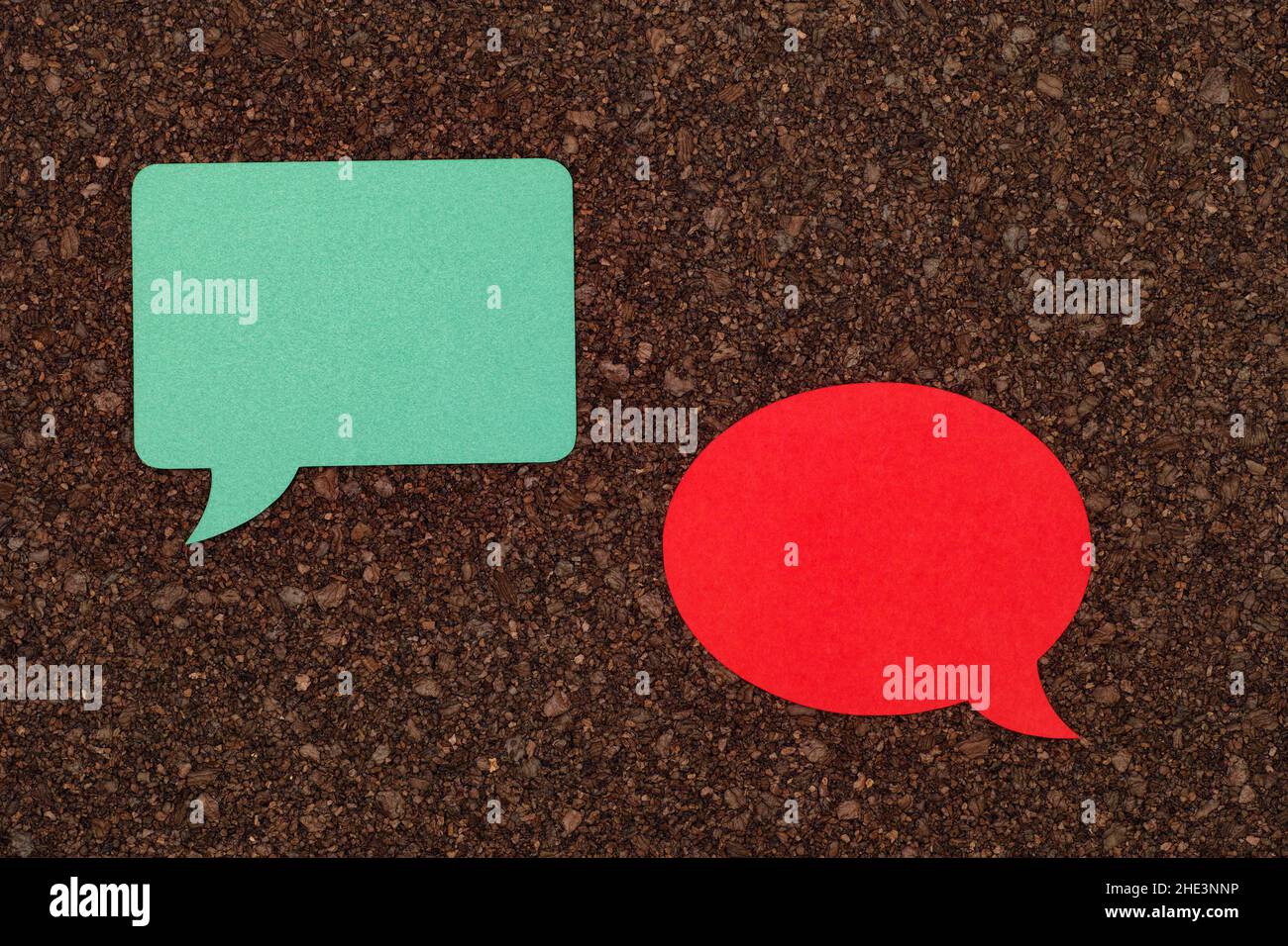 Two speech bubbles laying on a cork board. Close up. Stock Photo
