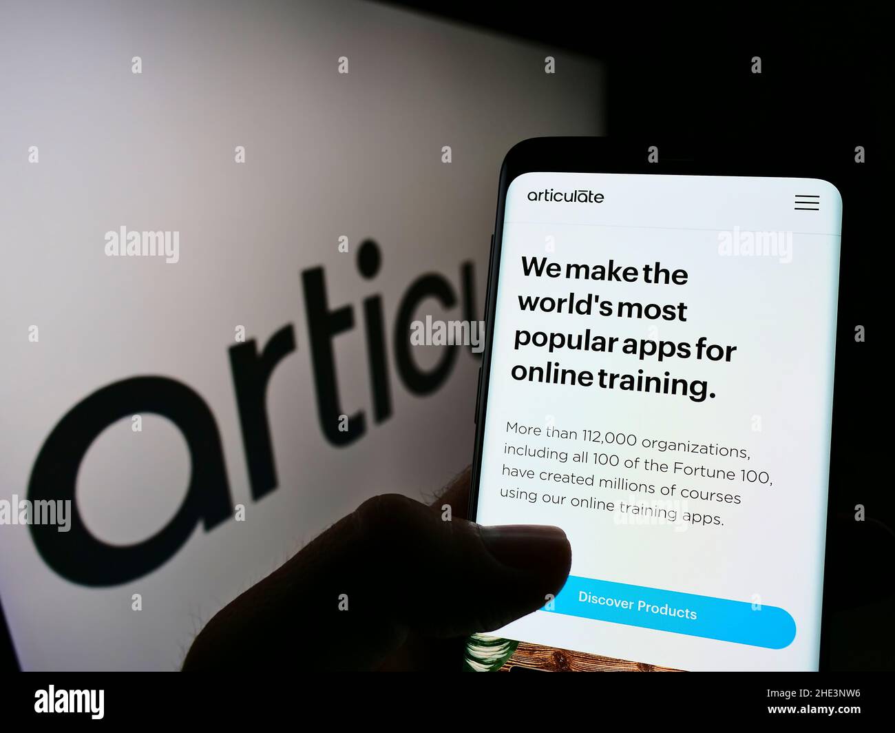 Person holding cellphone with webpage of US e-learning company Articulate Global LLC on screen in front of logo. Focus on center of phone display. Stock Photo