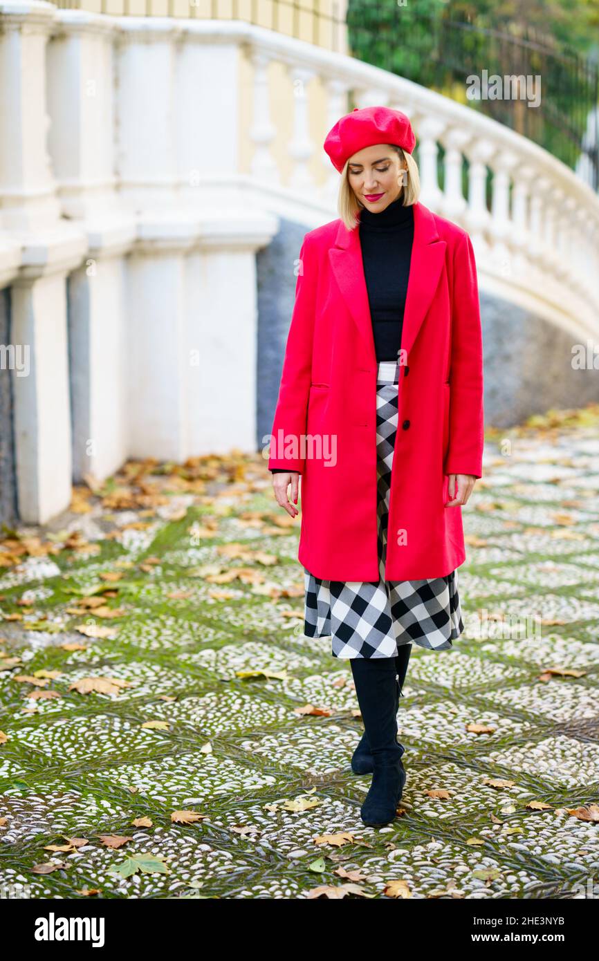 Middle-aged woman wearing red winter clothes walking through an urban park. Stock Photo