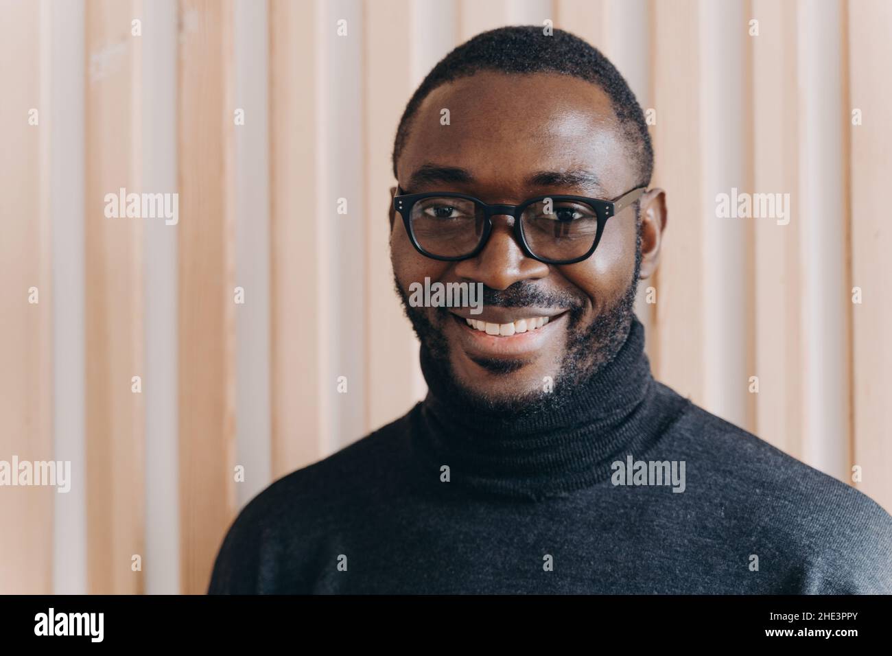 Elegant confident Afro american businessman in glasses posing while standing in modern office Stock Photo