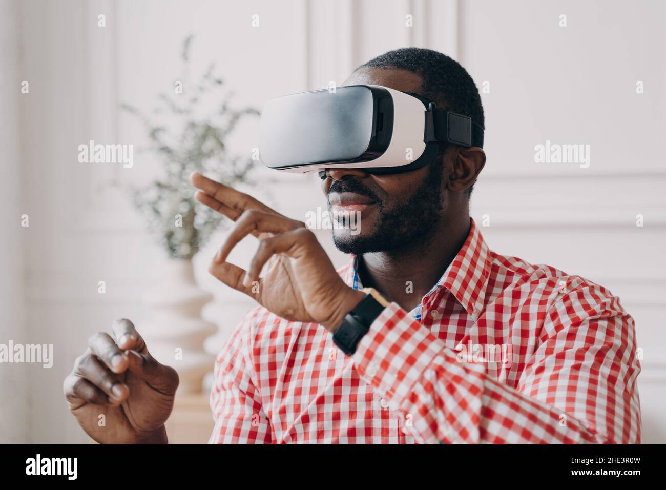 Young african businessman wearing VR glasses touching 3d objects, interacting with virtual reality Stock Photo