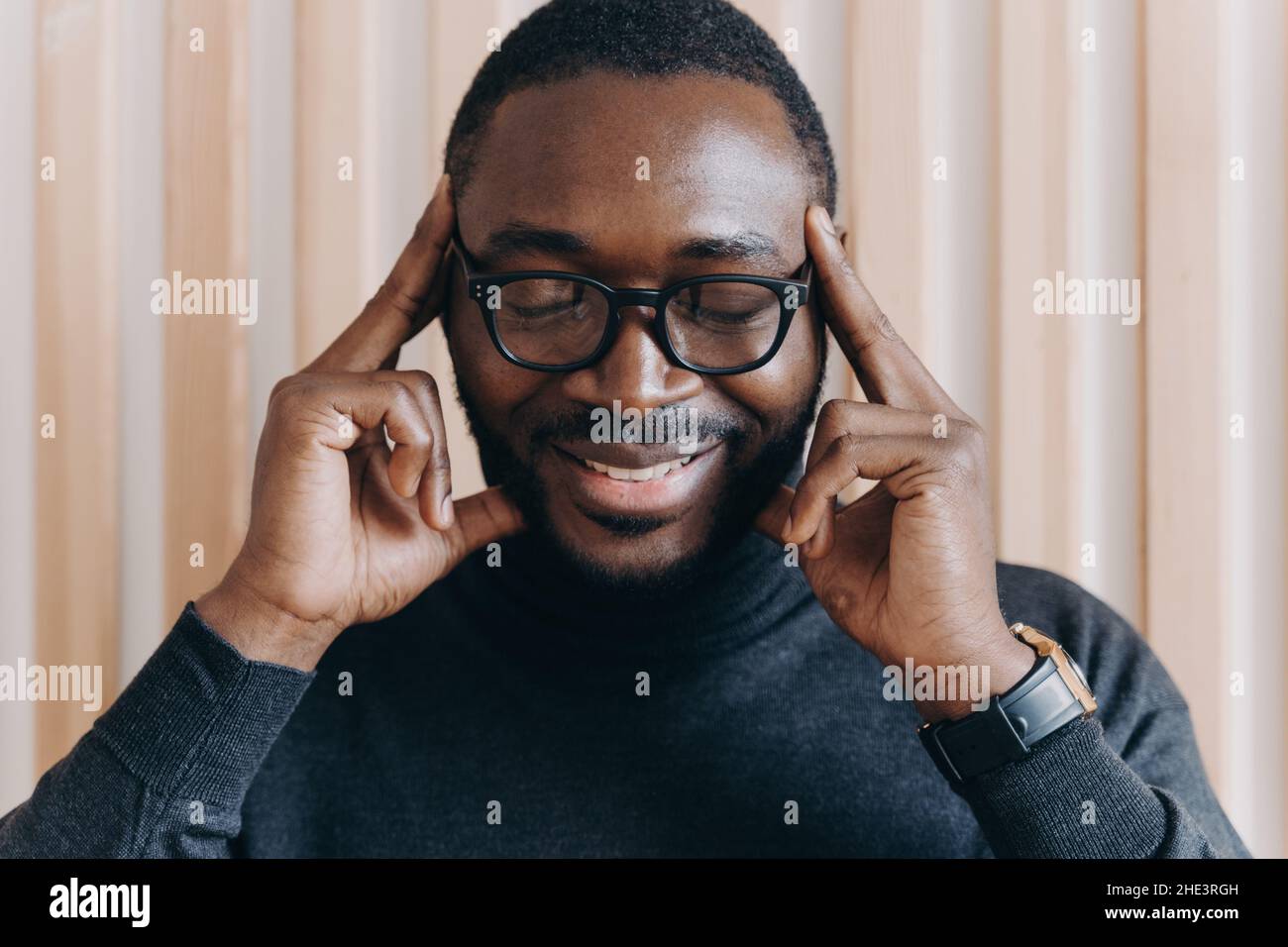Thoughtful African American male entrepreneur with closed eyes touching temples with forefingers Stock Photo