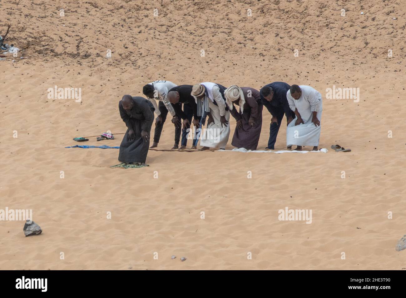 A group of muslim men do their daily ritual prayer, Salat, on the banks of the Nile in Aswan, Egypt. Stock Photo