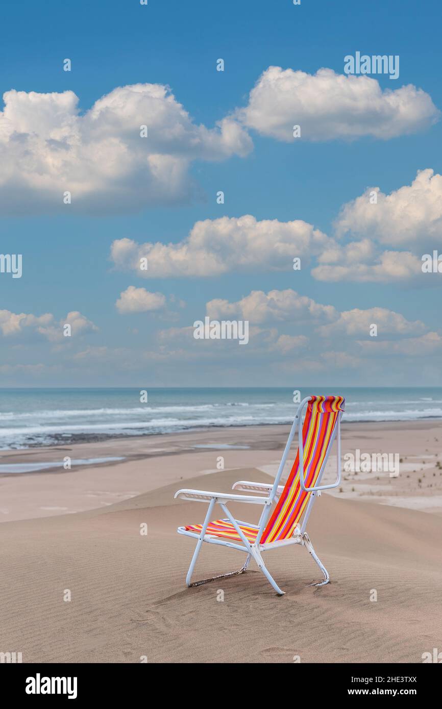 Empty striped beach chair on top of a dune facing the sea. Vertical photo Stock Photo
