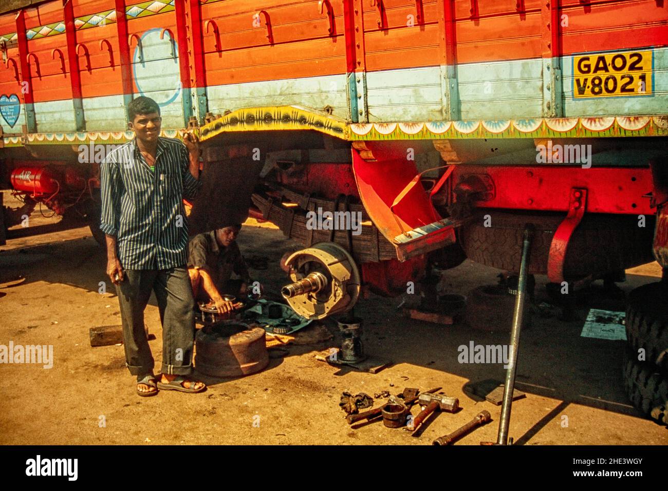 Truck mechanic posing with the lorry he is working on in the open air, Goa, India Stock Photo