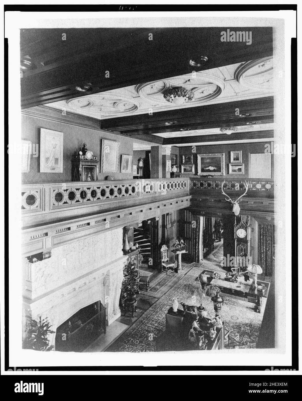 Room with balcony, paintings, fireplace, grandfather clock, and elk head, in home of Edmund Cogswell Converse, Greenwich, Connecticut Stock Photo