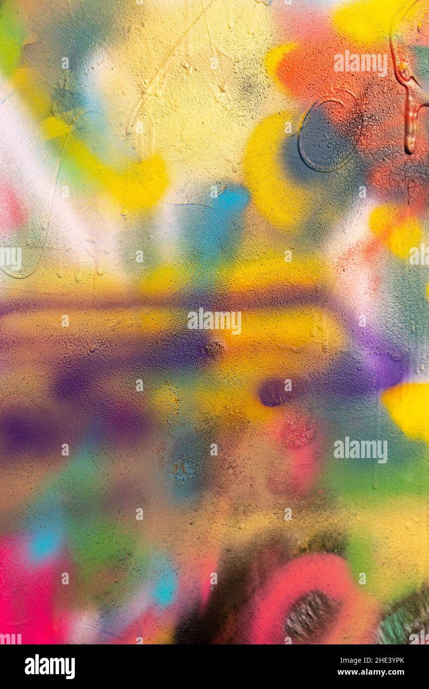 Some colorful and splattered spray paint graffiti over a cracked