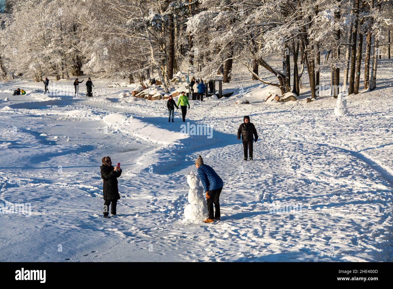 People on snow covered Munkkiniemi Beach on a sunny winter day in Helsinki, Finland Stock Photo