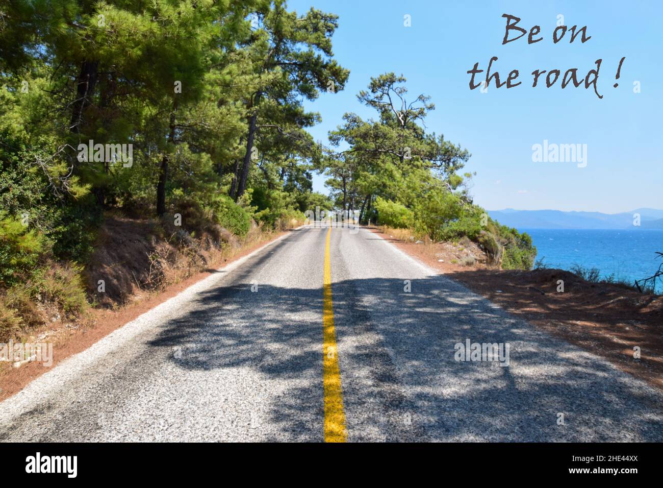 Scenic roadway by the blue sea and forest, be on the road, be free, roam the world. Stock Photo