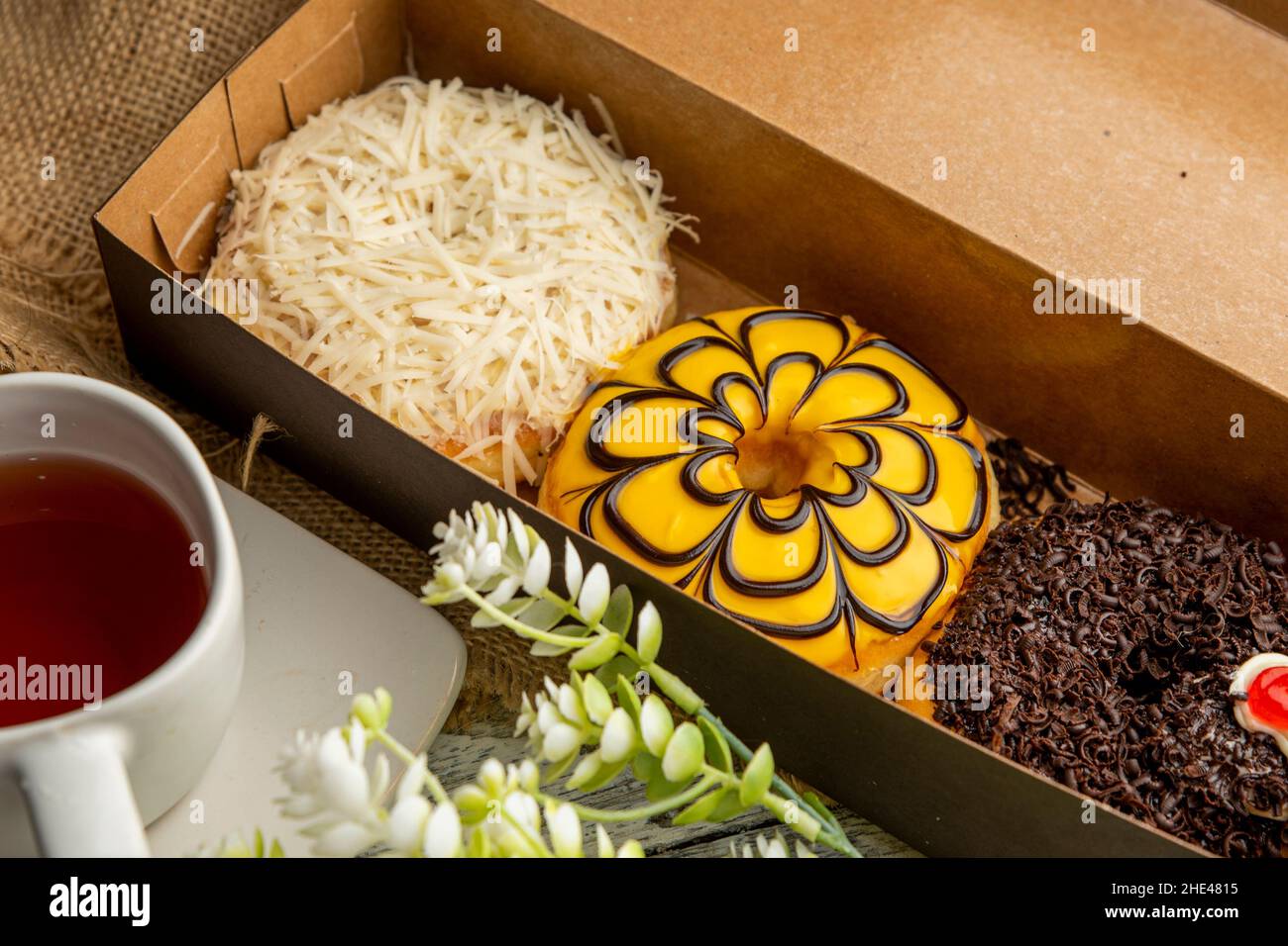 High-angle shot of fresh and delicious donuts and a cup of tea on the table Stock Photo