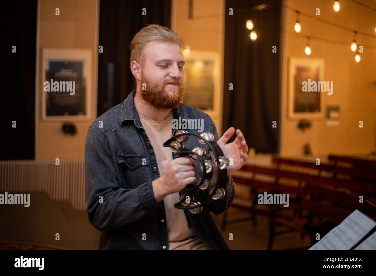 A young guy with a beard plays the tambourine Stock Photo Alamy