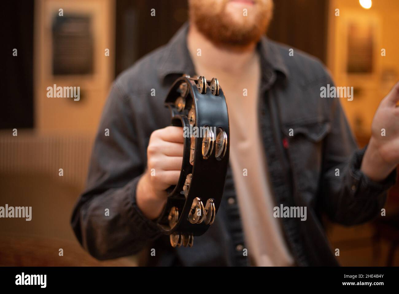 A young guy with a beard plays the tambourine Stock Photo Alamy