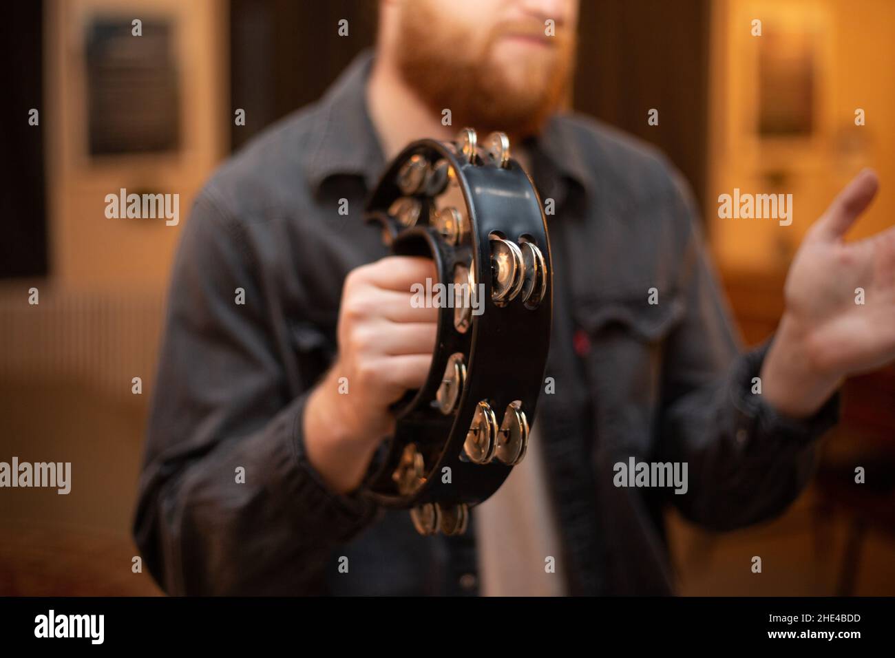A young guy with a beard plays the tambourine Stock Photo Alamy