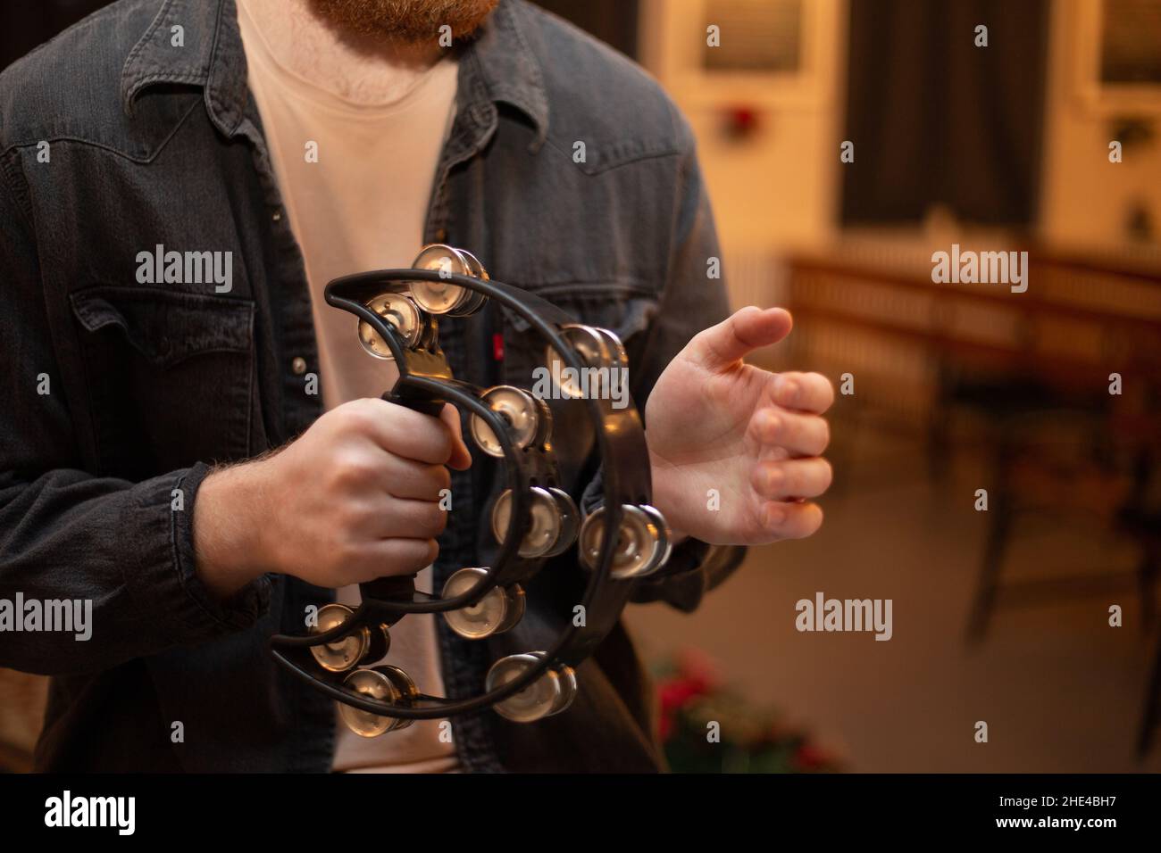 A young guy with a beard plays the tambourine Stock Photo Alamy