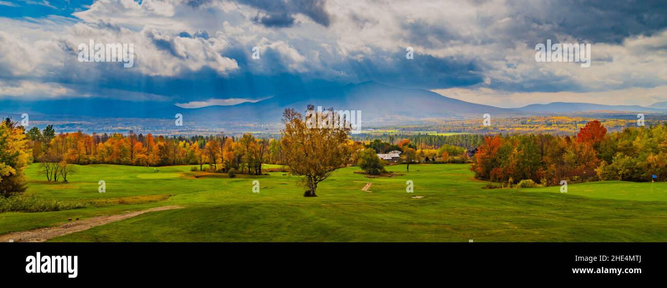 light breaks through dramatic clouds lightening up fall foliage after the rain on a autumn day Stock Photo