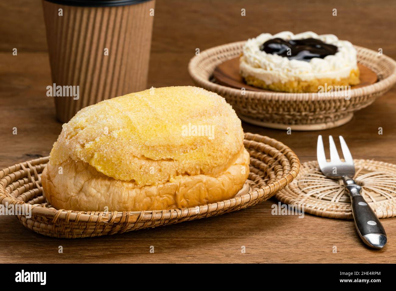 Breakfast with delicious sweet Fresh Butter Bread on bamboo tray, Blueberry Cheese Pie in bamboo basket, a cup of coffee and metal fork on a mat on wo Stock Photo