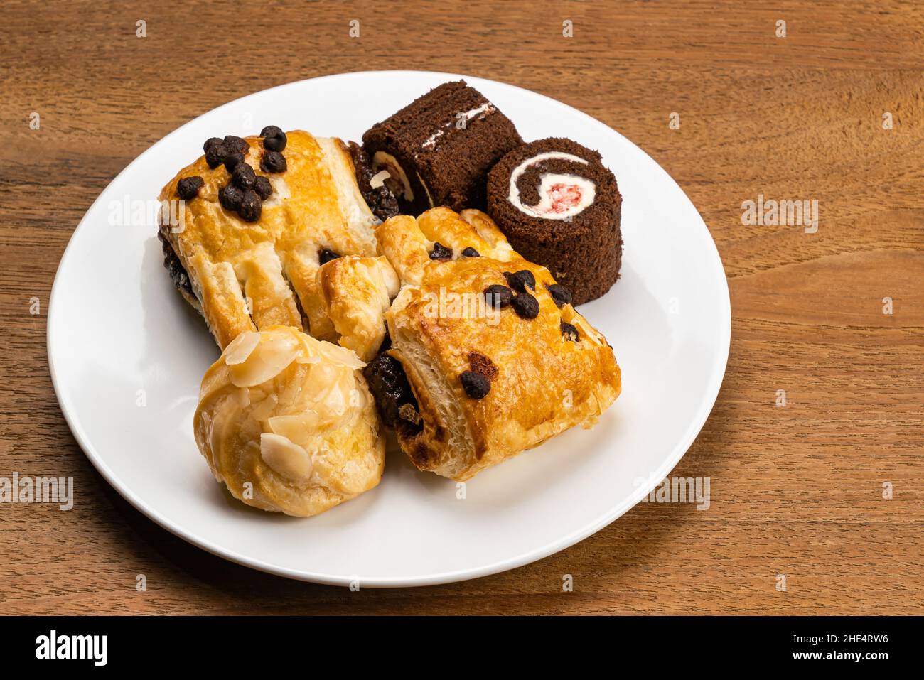 Various baked pastry dessert in white ceramic dish. Assortment of homemade dessert, Eclair filled with sweet corn cream, Danish Pastry filled with cho Stock Photo