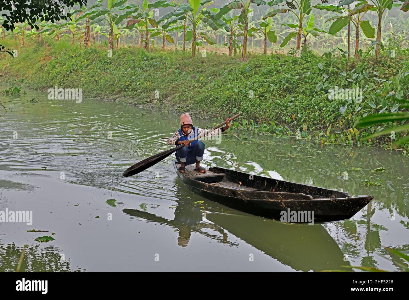 Boatman paddling his boat upstream Stock Photo