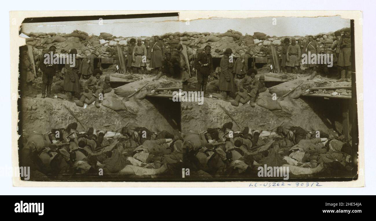 Russian soldiers looking down at a trench filled with corpses of ...