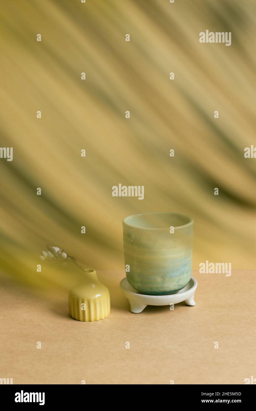 Ceramic tea cup with dry plant on brown table background Stock Photo