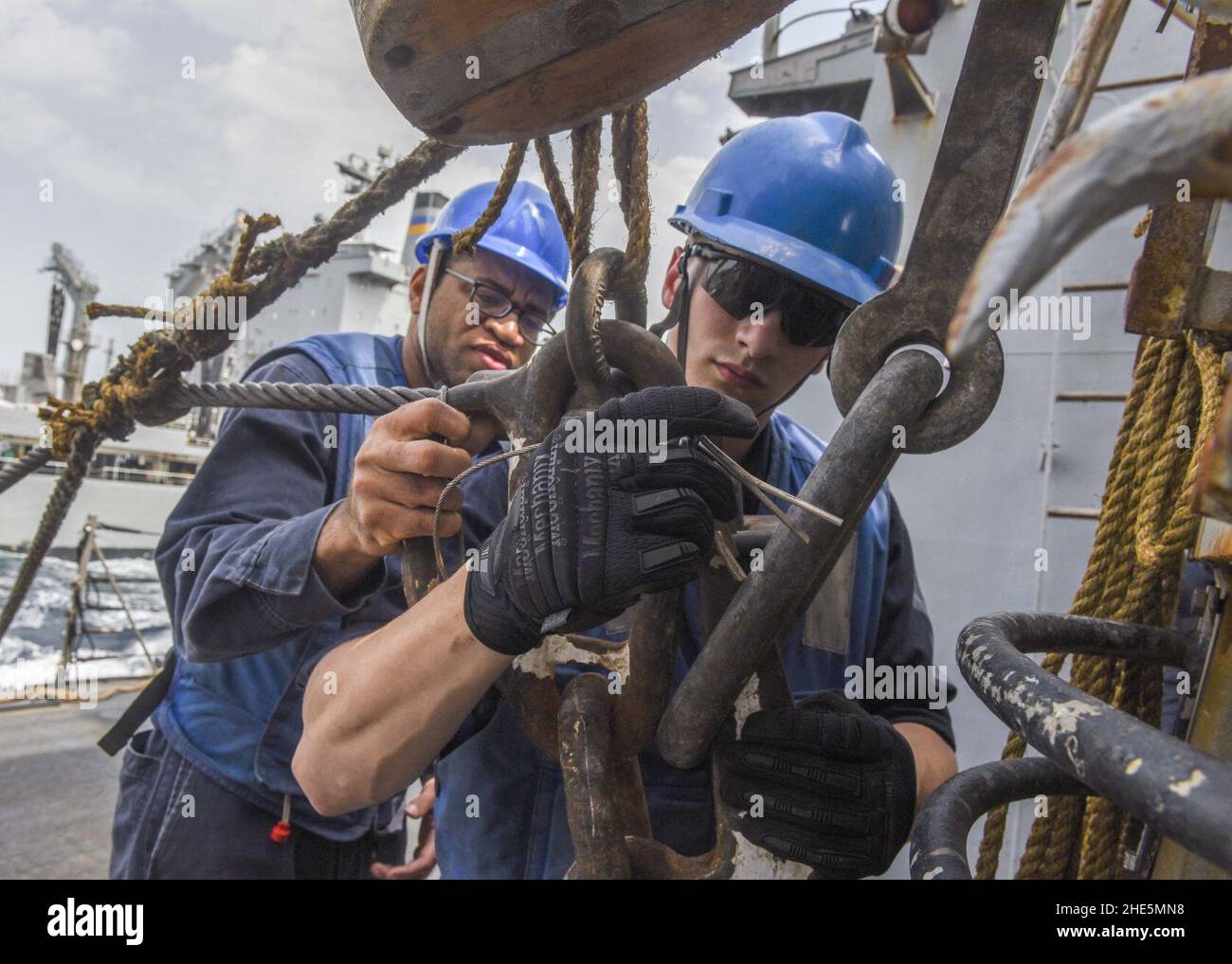 Sailors connect a span wire to a kingpost cargo station aboard USS ...