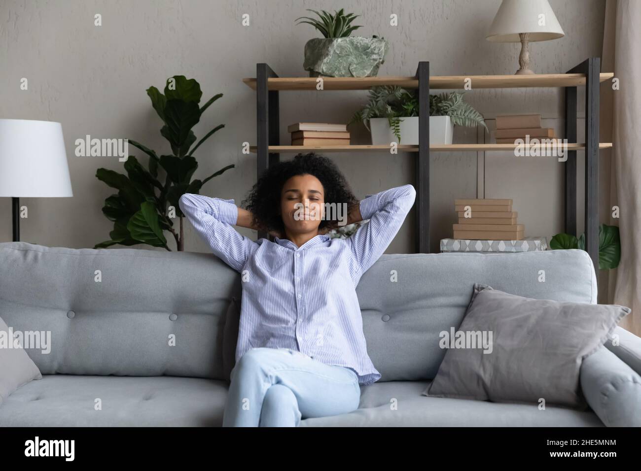Happy young african woman relaxing on cozy sofa Stock Photo - Alamy