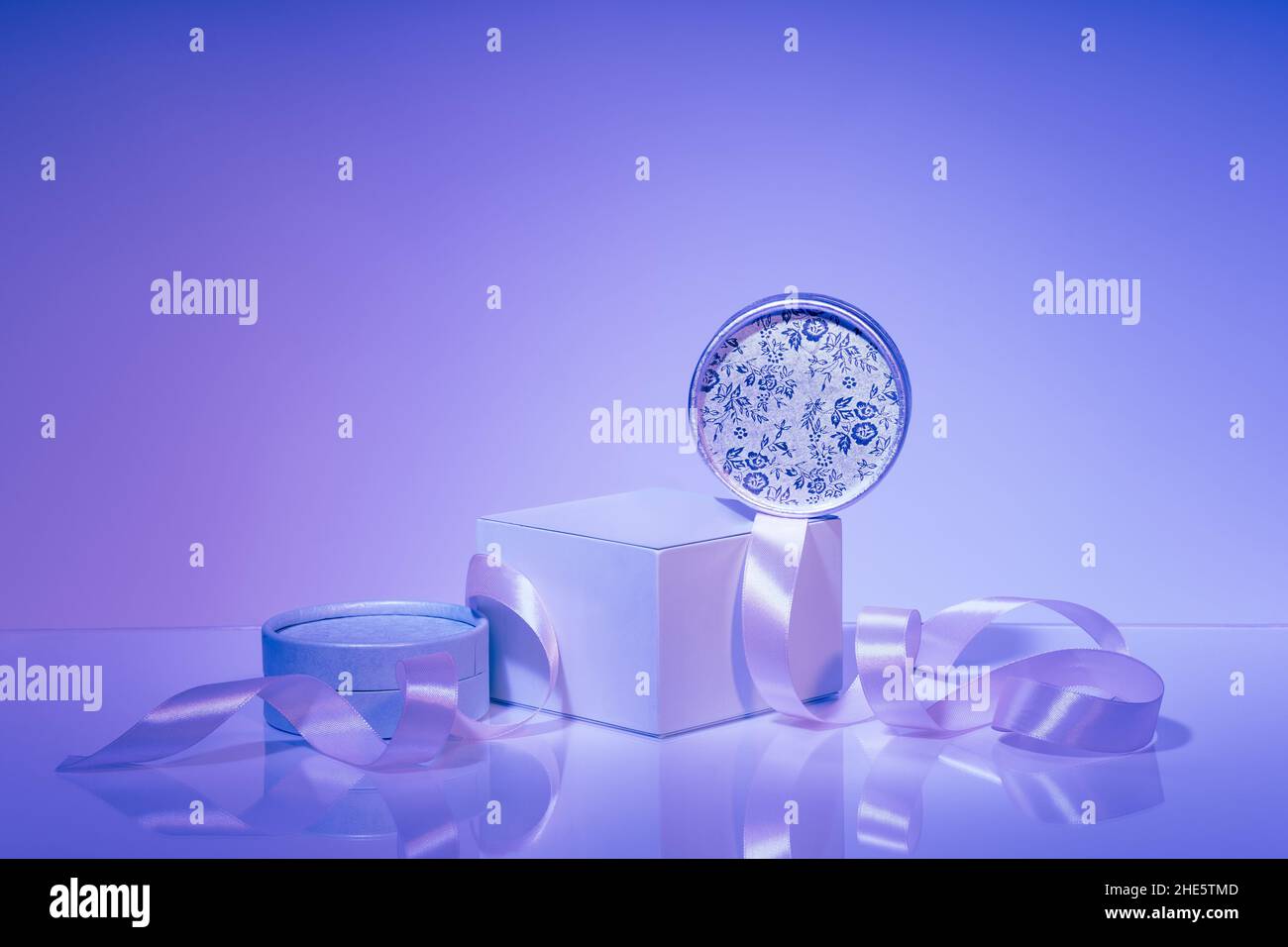 Podium, assorted gift boxes with satin ribbon on purple background Stock Photo