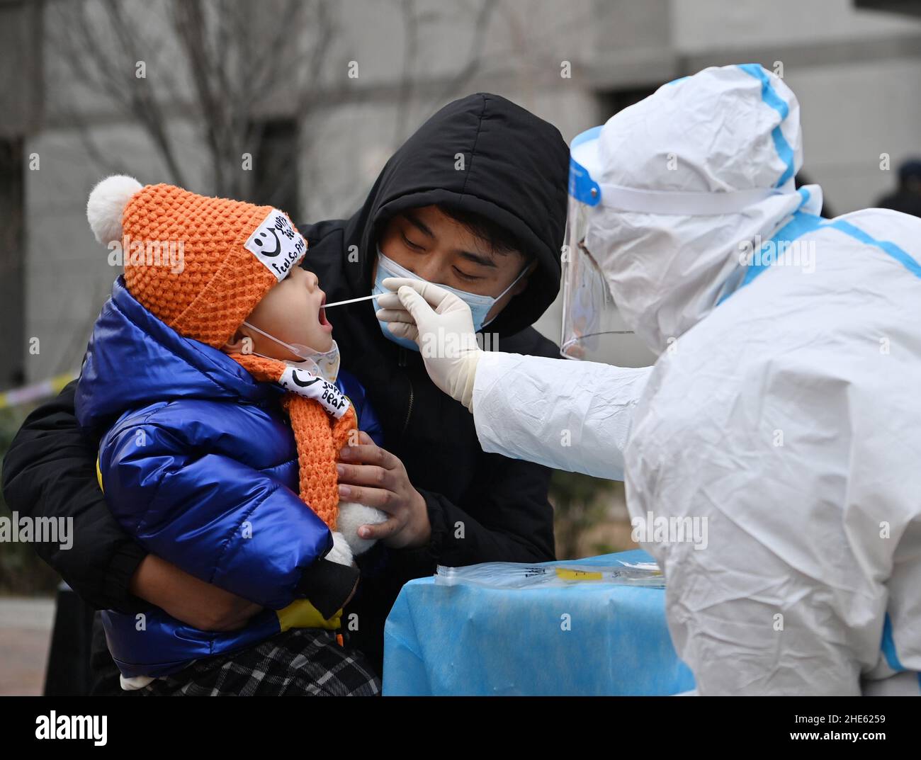 Tianjin, China. 09th Jan, 2022. A parent holds a child for nucleic acid test at a testing site of a residential area in Xiqing District in north China's Tianjin, Jan. 9, 2022. North China's Tianjin, a municipality that neighbors Beijing, has decided to start a citywide nucleic acid testing after 20 people tested positive for COVID-19, authorities said Sunday. The infections were reported from 6 p.m. Friday to 9 p.m. Saturday in Jinnan District, and the gene sequencing found the first two locally transmitted confirmed cases were infected with the VOC/Omicron variant, according t Credit: Xinhua/ Stock Photo