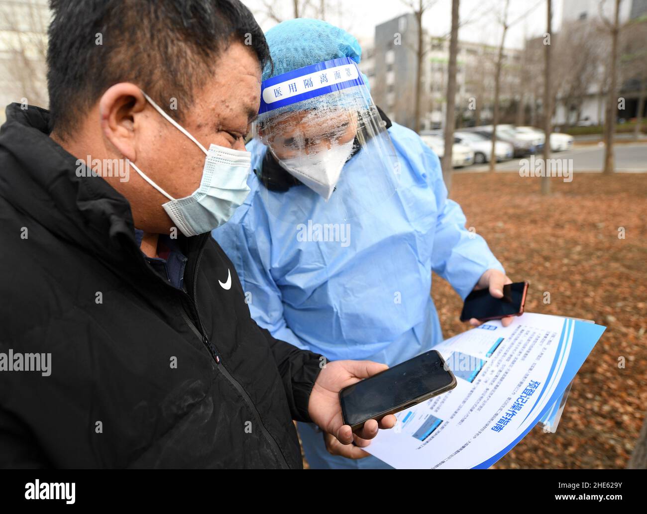 Tianjin, China. 09th Jan, 2022. A staff member helps a citizen go through registration procedure for nucleic acid test at a testing site in Binhai New Area in north China's Tianjin, Jan. 9, 2022. North China's Tianjin, a municipality that neighbors Beijing, has decided to start a citywide nucleic acid testing after 20 people tested positive for COVID-19, authorities said Sunday. The infections were reported from 6 p.m. Friday to 9 p.m. Saturday in Jinnan District, and the gene sequencing found the first two locally transmitted confirmed cases were infected with the VOC/Omicron Credit: Xinhua/A Stock Photo