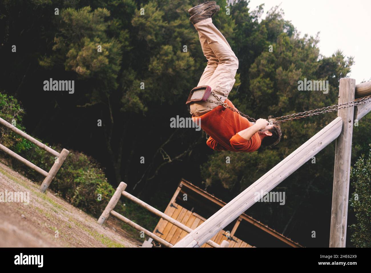Adult man play and have fun flying high on swing at the park - happy aged people enjoying outdoors freedom concept lifestyle Stock Photo