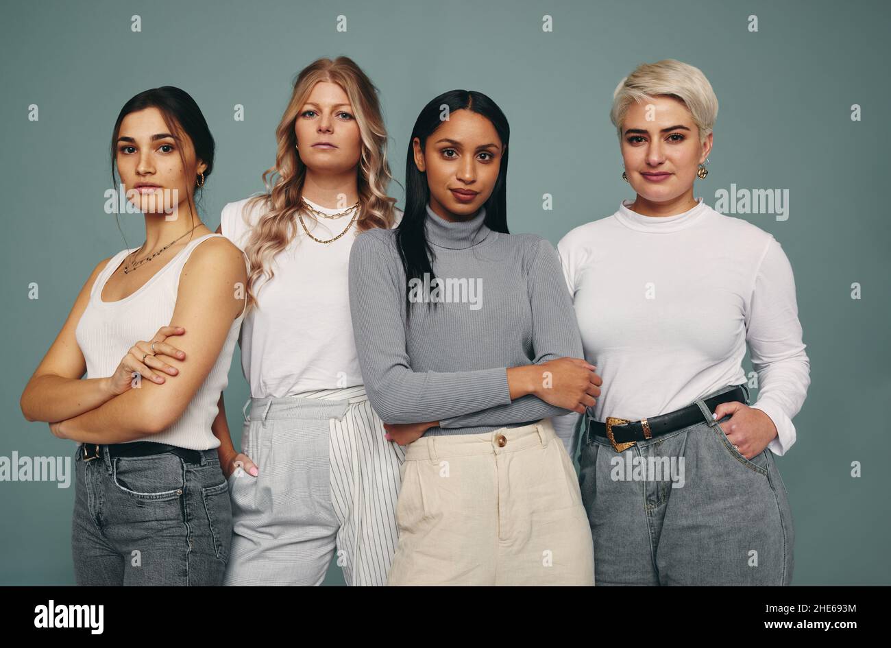 Diverse and beautiful. Group of fashionable women looking at the camera while standing together against a studio background. Four female friends looki Stock Photo