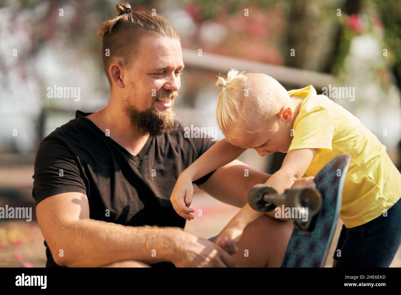 Father is spending quality time with with his little son in skate park Springtime. Family time together Stock Photo